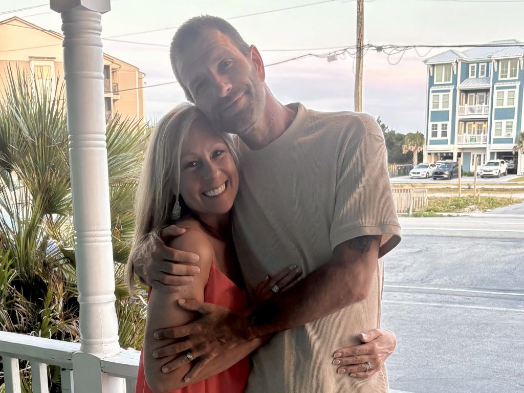 A newly married Christian couple pose on the porch overlooking a street