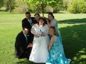 A wedding party surrounds a beautiful bride on the grass on her wedding day