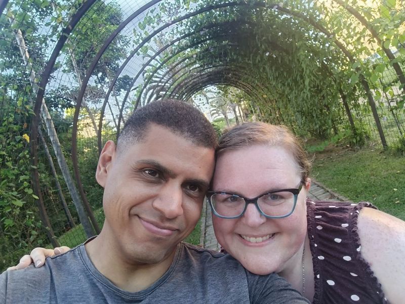 A happy couple lean in for a selfie under a canopy tunnel of trees