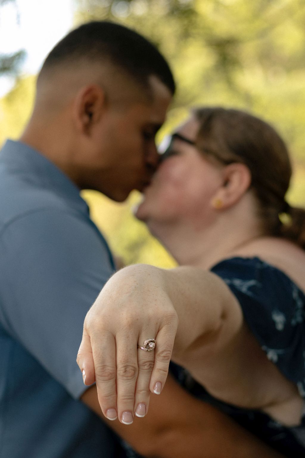 A woman shows off her new engagement ring as she and her fiance kiss