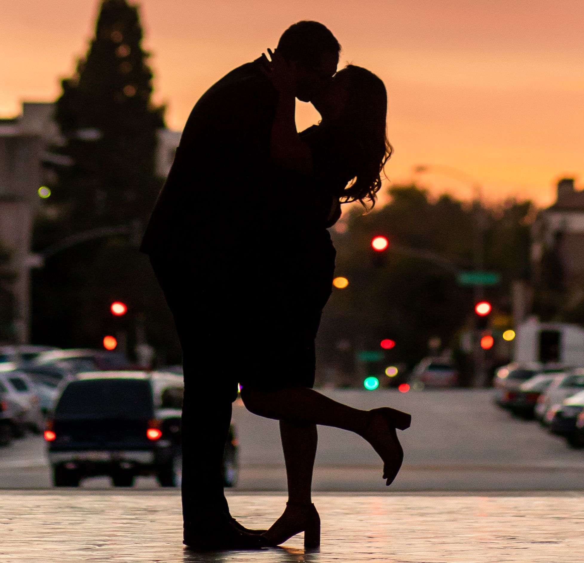 A silhouette of a couple kissing at sunset in the city