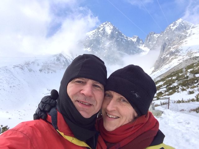 Mountain vacation for Christian couple with mountains behind them as they snuggle in winter clothes
