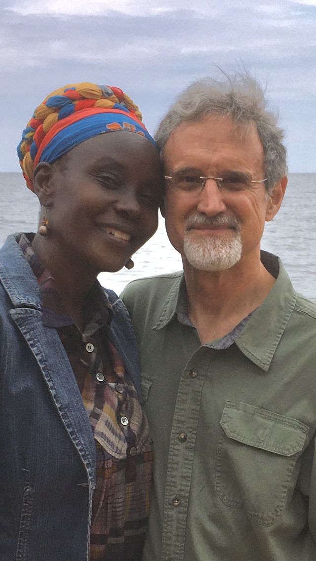 An interracial couple snuggles on the edge of a lake