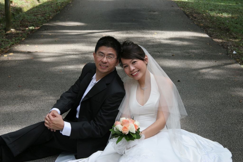 Christian newlyweds smiling and sitting on pavement just after marrying