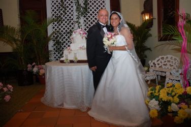 Excited Christian couple smile together next to their wedding cake