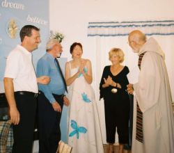 A bride claps her hands with joy as she stands next to her new Christian husband