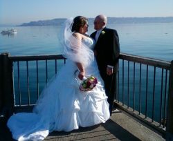 A gorgeous view of the ocean with a romantic couple standing next to each other at a lookout, on their wedding day