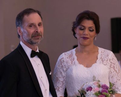 New Christian bride smiles next to her husband while looking at her beautiful bridal bouquet
