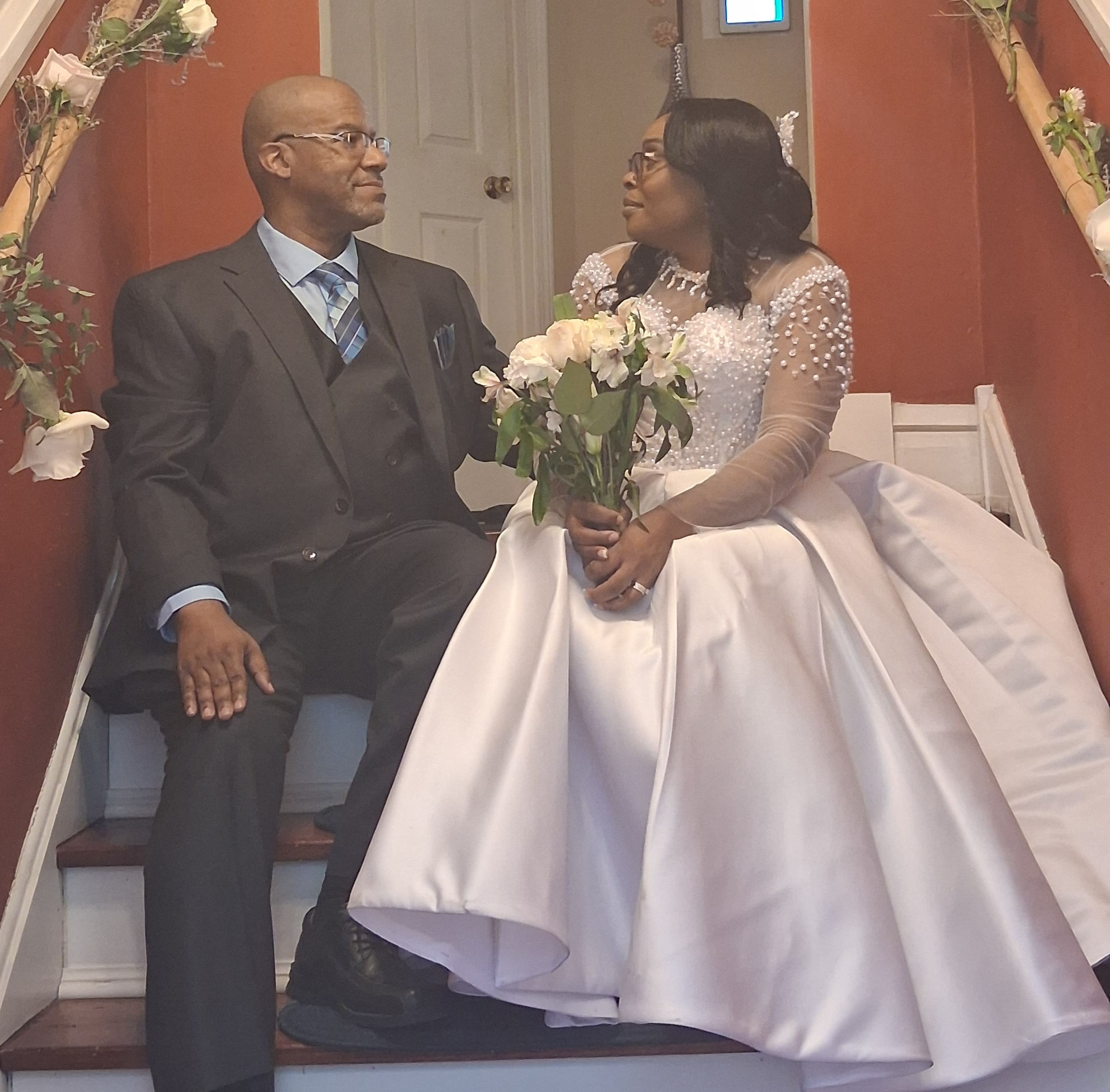 A groom and bride sit facing each other in a stairwell after marrying