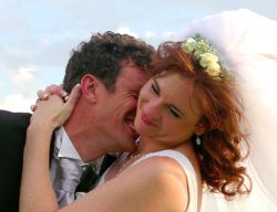 A very happy groom laughs and buries his head in his bride's shoulder as she smiles