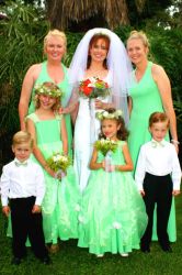 A bride in white is surrounded by her bridesmaids in green